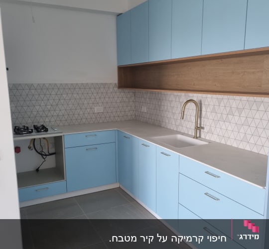 מטבח עם ארונות כחולים, כיור וברז זהב